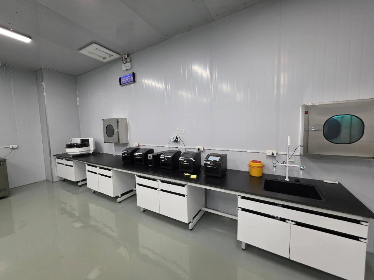 Laboratory instruments arranged along a black workbench beside a sink
